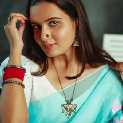 A beautiful close-up portrait of a model in a light blue saree, looking directly at the camera with a confident and engaging expression.