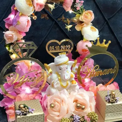 An elaborate engagement ring platter featuring a Ganesha idol, personalized name cutouts, and beautiful floral decorations with fairy lights.