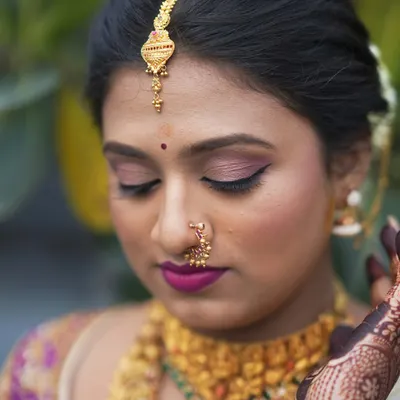 A close-up of Pooja's wedding makeup. The soft pink eyeshadow and bold magenta lip perfectly complement her traditional attire, creating a fresh and vibrant bridal look.