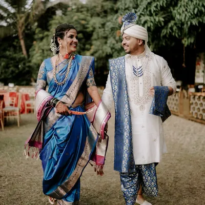 A beautiful moment between the bride and groom, captured outdoors. The bride looks radiant in her royal blue Paithani saree, a classic choice for Maharashtrian weddings, showcasing the rich textile heritage.