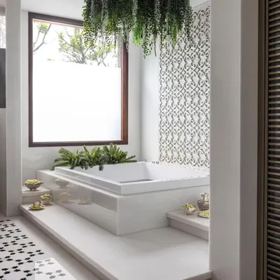 This is a home spa we designed to be a bright, airy sanctuary. The jacuzzi is surrounded by white marble and lush greenery, with a hanging plant installation that adds a touch of drama. The intricate mother-of-pearl jaali on the wall is a beautiful example of detailed craftsmanship.