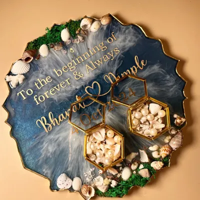 This is one of the prettiest ocean-themed ring platters I've made. It features deep blue resin with white lacing to create wave effects, a border of real seashells, and hexagonal glass ring boxes filled with pearls and shell fragments.