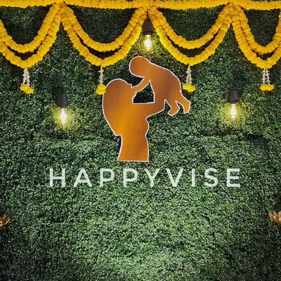 A modern take on Haldi decor, this backdrop features a green foliage wall decorated with marigold garlands. The silhouette of a mother and child adds a personal, heartwarming touch.
