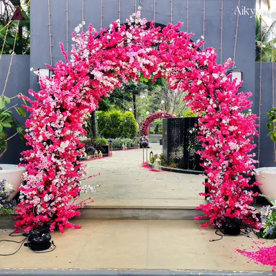 A stunning entrance arch made entirely of vibrant pink and white cherry blossoms. This creates a magical and romantic pathway for guests, setting a beautiful tone for the event.