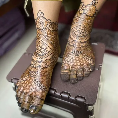 A close-up of a bridal feet design. The pattern is dense and intricate, with a beautiful floral band around the ankle, perfectly framing the foot.