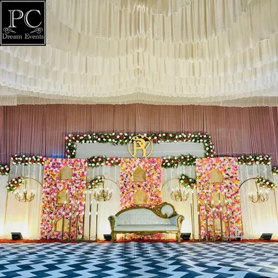 A full view of a grand wedding stage. I used a striking black and white chevron floor, a massive floral wall with alcoves, and a royal white sofa to create a high-impact, glamorous look.