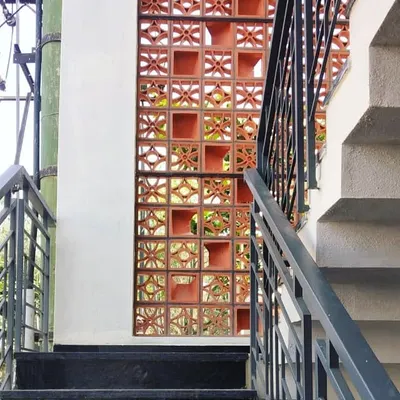 A terracotta jaali screen provides a beautiful, porous barrier for a staircase. It allows for ventilation and the passage of dappled light while adding a rich, earthy texture to the space.