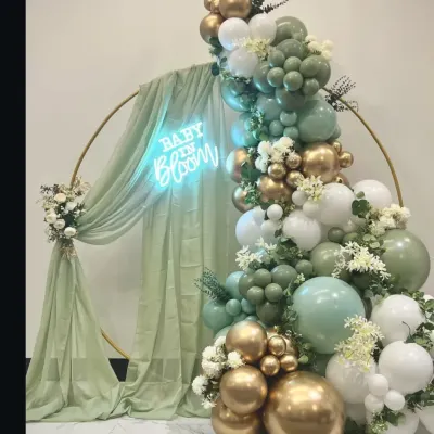 A beautiful 'Baby in Bloom' backdrop I designed for a baby shower. The sage green, white, and gold balloon arch with a custom neon sign is a popular and elegant choice.
