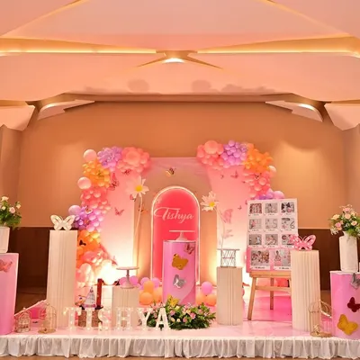 A wide view of a butterfly-themed stage, featuring large cutout wings and soft pink lighting. This setup is perfect for a grand hall and creates a beautiful photo opportunity.