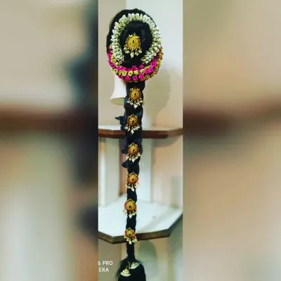 A full view of a traditional 'poola jada' hairstyle for a bride. The long braid is heavily adorned with jasmine flowers and gold ornaments, creating a grand and customary look for a muhurtham ceremony.