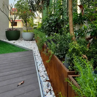 At the 'House of Terraces,' I used Corten steel planters to create a warm, tactile boundary between the deck and the greenery. A pebble-filled drainage channel is both a functional solution and a beautiful design detail.