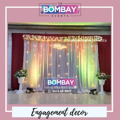 A full view of our engagement stage decoration. The combination of rich red and sheer white drapes, a dense floral runner, hanging accents, and soft uplighting creates a sophisticated and romantic setting for your ring ceremony.