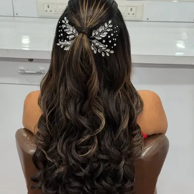 A modern and chic hairstyle for a reception or sangeet. This half-up style with soft curls is accented with a beautiful crystal bow clip.