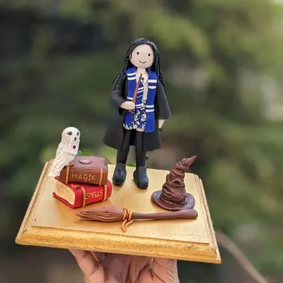 Indulge in some Harry Potter magic. This cake topper was for a special girl's birthday, and it was the fifth consecutive year I've had the honor of creating a topper for her celebration. It features a custom figurine, Hedwig, spell books, a broom, and the sorting hat.