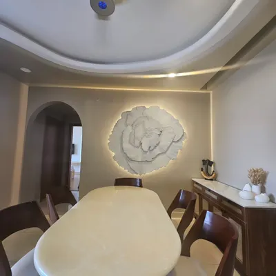 The 3D floral art installed in a client's dining room, where the backlighting creates a soft, ambient glow. It serves as a serene and elegant focal point, complementing the modern interior.