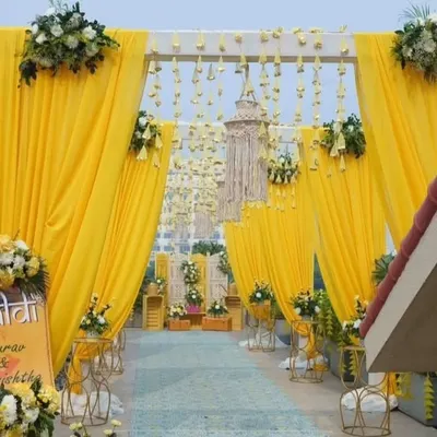 An inviting entrance I created for a Haldi ceremony, with bright yellow drapes and hanging floral tassels. The custom welcome sign for Gaurav and Sanchikha adds a personal touch right from the start.