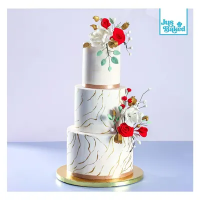 This three-tier wedding cake features a striking marble effect with gold veining, accented by handmade red and white sugar flowers. It's a modern and artistic choice for a memorable wedding day.