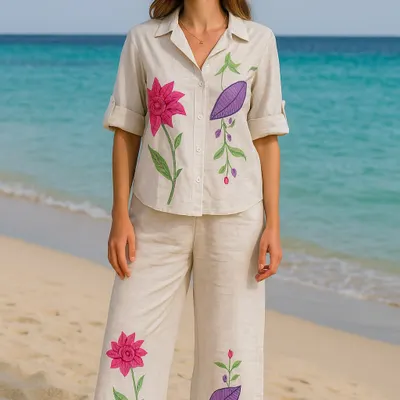 This embroidered co-ord set is your perfect vacation companion, shown here against a beautiful beach backdrop. The breathable cream fabric features vibrant pink and purple floral embroidery, offering a different color variation of our popular travel set. The relaxed shirt and pants are both stylish and comfortable for all-day wear.