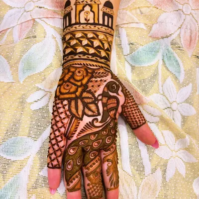This design combines a royal palace dome on the wrist with a magnificent peacock on the palm. The use of geometric patterns and intricate shading gives it a classic, regal look.