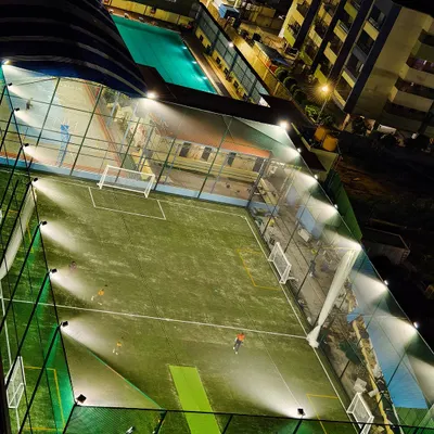 An aerial view of our state-of-the-art football turf, inaugurated and ready for action under the bright floodlights for evening and night matches.