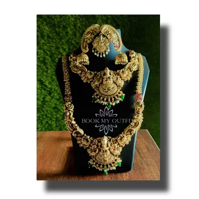 This is one of our most popular rental pieces for brides. It’s a complete, heavy temple jewelry set with intricate carvings, a layered long necklace, a matching choker, and jhumka earrings, all in a classic antique gold finish.