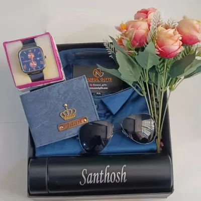 This complete gift hamper in a blue theme includes a personalized wallet, a name-engraved temperature bottle, a watch, sunglasses, and a shirt, all beautifully presented with a floral touch.