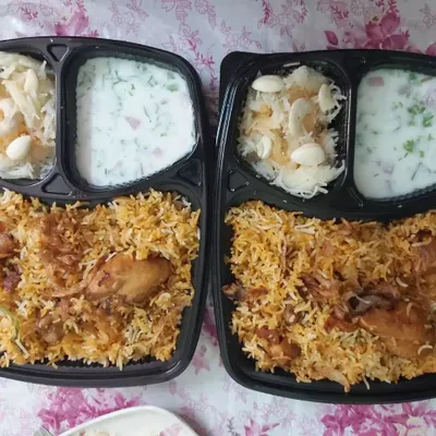 Two freshly packed chicken biryani meal boxes, perfect for sharing with a friend or colleague. Each box contains a generous portion of biryani, raita, and a side of sweet seviyan.