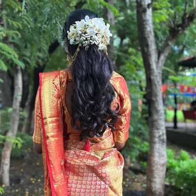 A beautiful half-up, half-down hairstyle with soft curls, adorned with fresh white flowers. This is a classic choice for South Indian brides and looks incredibly romantic.