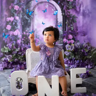 A magical first birthday in an enchanted purple forest. This little one is captivated by the fluttering butterflies in this dreamy, creative setup.