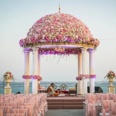 A breathtaking mandap with a dome made entirely of pink and peach roses, set against the serene water. This is the epitome of a fairytale wedding, where my team and I turn romantic dreams into reality.