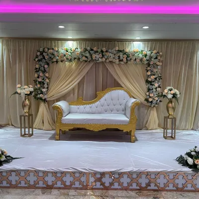 A classic and elegant stage for a reception or engagement. I used a beautiful white and gold Diwan sofa, a backdrop of cream-colored drapes, and a floral arch with white and peach roses.