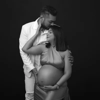 Pure love in every frame. This black and white portrait captures a tender moment, with the dad-to-be placing a gentle kiss on his partner's forehead.