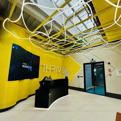 The reception of the 8,000 sq ft DLF Thrive Gym in Chennai. The vibrant yellow accents pay homage to the city's spirit, while the custom 'noodle' light fixture adds a unique, energetic touch to the entrance.
