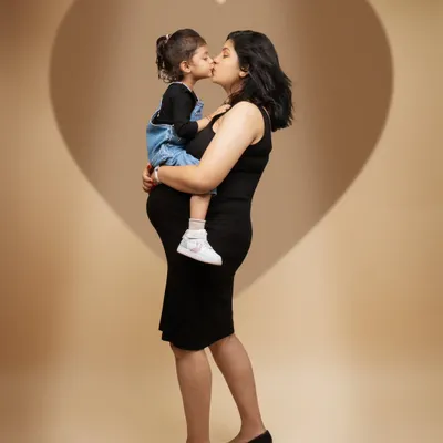 A love that grows with every heartbeat. This portrait captures a mother holding not just her little one, but also the new life growing within her, all framed by a heart of light.