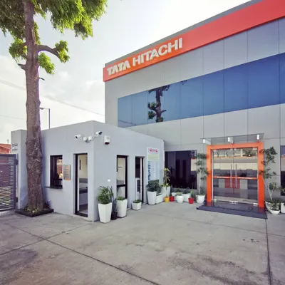 The main entrance of the award-winning Tata Hitachi dealership. The design combines a professional gray facade with the brand's signature orange, creating a welcoming yet authoritative presence that reflects the company's identity.