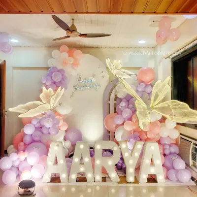 A stunning butterfly theme for a first birthday, featuring large marquee letters, pastel balloons, and oversized, elegant butterfly wings.