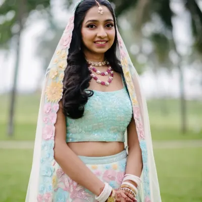 A radiant close-up portrait of the bride in her pastel lehenga, smiling beautifully against a soft, natural background in Goa.