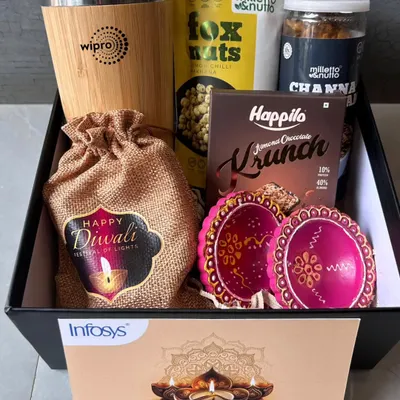 This festive hamper, featuring a Wipro branded mug, is packed with treats like fox nuts, chana, and chocolate, along with painted diyas and a custom Diwali card. It's a perfect blend of utility and celebration.