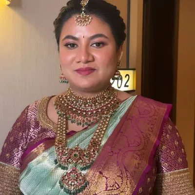 A close-up of a traditional Seemantham makeup look. The skin is smooth and radiant, and the lip color is chosen to perfectly balance the heavy gold jewelry.