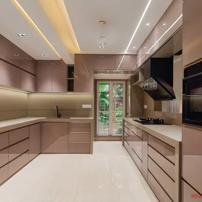 A beautiful and spacious U-shaped kitchen with rose-gold toned, back-painted glass panels. The layout provides ample counter space and storage, with integrated lighting to create a luxurious and functional cooking environment.