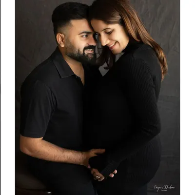 An intimate moment between partners, captured in a classic studio setting. The focus on simple, dark tones allows the emotion and connection to be the true highlight of the portrait.