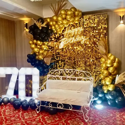 For a glamorous 70th birthday, we designed this stunning photo booth with a gold shimmer wall, a custom 'Happy Birthday' neon sign, and bold marquee numbers. The black and gold balloon arrangement adds a touch of sophisticated fun.