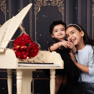 Sisters making music together. A sweet moment between an older and younger sister at our miniature piano.