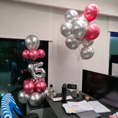 We help you celebrate your team members with personalized desk-side surprises. This setup includes a bouquet of helium balloons and a foil number balloon to mark a 15-year work anniversary, creating a special moment for the employee.