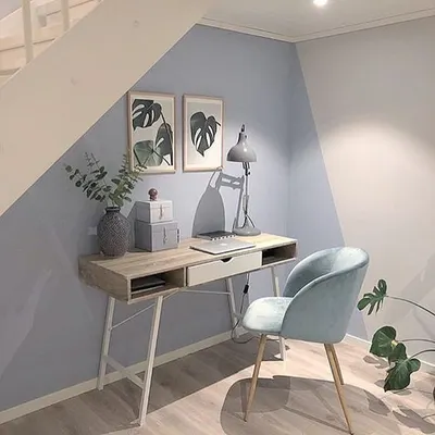 This study area, neatly tucked under a staircase, is defined by a two-tone diagonal paint design. This creative use of color transforms an awkward space into a stylish and functional home office nook.