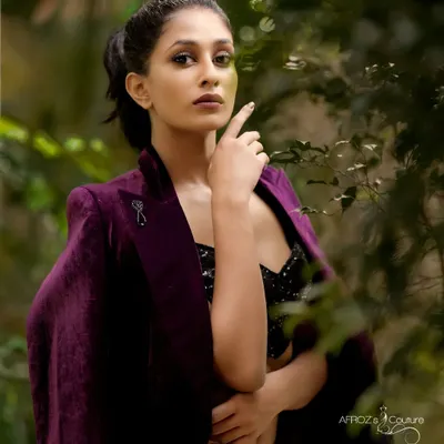 A model wearing a custom purple velvet two-piece set. This outfit includes a sequined bralette, high-waisted pants, and a matching velvet jacket, creating a luxurious and edgy look.