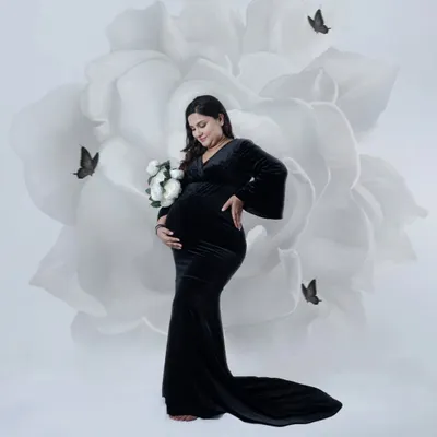 A striking portrait of a mother-to-be in a classic black gown. We used a digital backdrop of a large white flower to create a modern and artistic look.