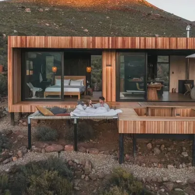 Imagine waking up to this. I design holiday homes that offer complete serenity, featuring unique elements like this deck hammock and an integrated hot tub for the ultimate relaxation experience.