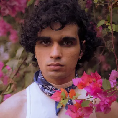 A creative outdoor portrait using flowers in the foreground to frame the subject's face. This technique adds depth and a unique artistic touch to a standard headshot.