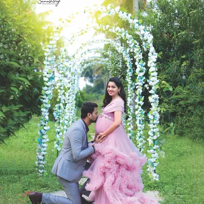 A fairytale moment in my private garden. The husband-to-be kneels to kiss the baby bump under a beautiful floral arch, creating a romantic and unforgettable memory.
